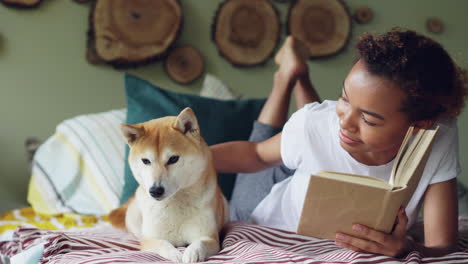 young woman reading with dog on bed