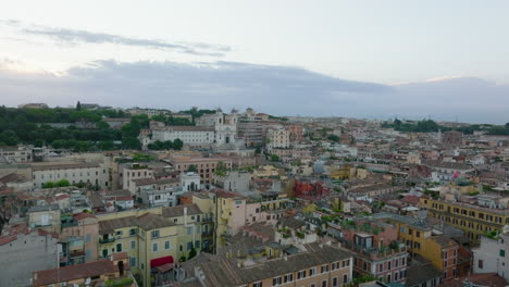 Forwards-fly-above-buildings-in-city-centre-at-twilight.-Heading-towards-renaissance-church-Trinita-dei-Monti.-Rome,-Italy