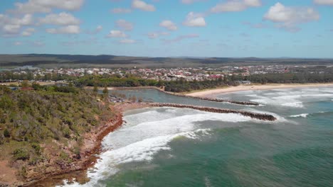 aerial view away from waves hitting the shore of the evans head village, sunny, summer day, in australia - reverse, drone shot