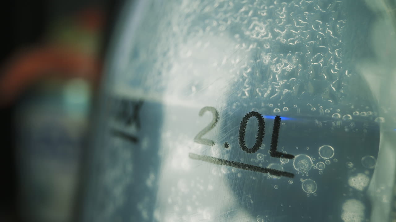 거품이 있는 투명한 액체가 병의 매크로에서  ⁇ 습니다.