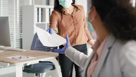 tracking video of women in protective gloves handing over document