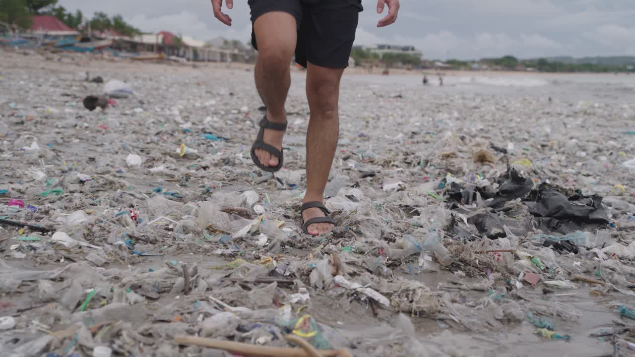 Persona che cammina tra l'inquinamento da plastica sulla spiaggia