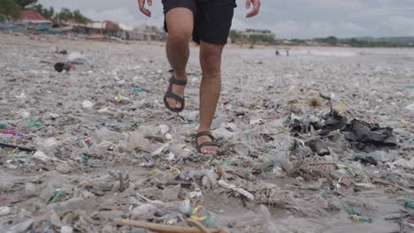person walking through plastic pollution on beach