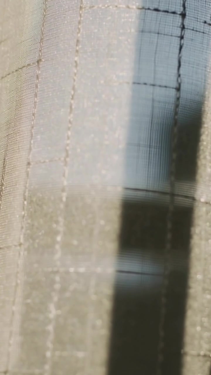 Vertical video: Swaying from small shift, sheer curtain with seams at window, revealing screen grid