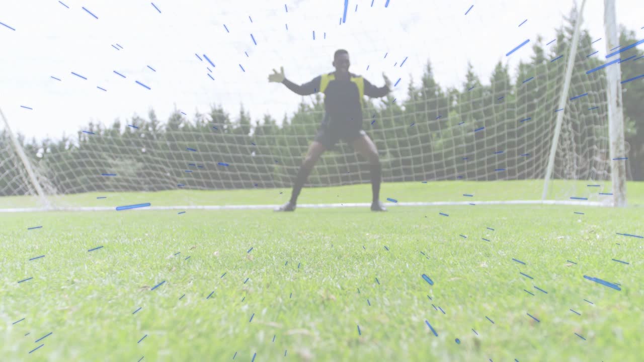Portiere di calcio che scatta verso il centro della porta preparandosi a difendere, mentre un attaccante scivola per raggiungere il pallone.
