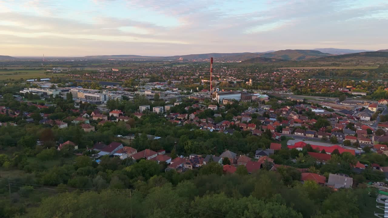 Ascending aerial view of the Dorog suburb and city center during sunset with the Pilis mountains in the background in Hungary