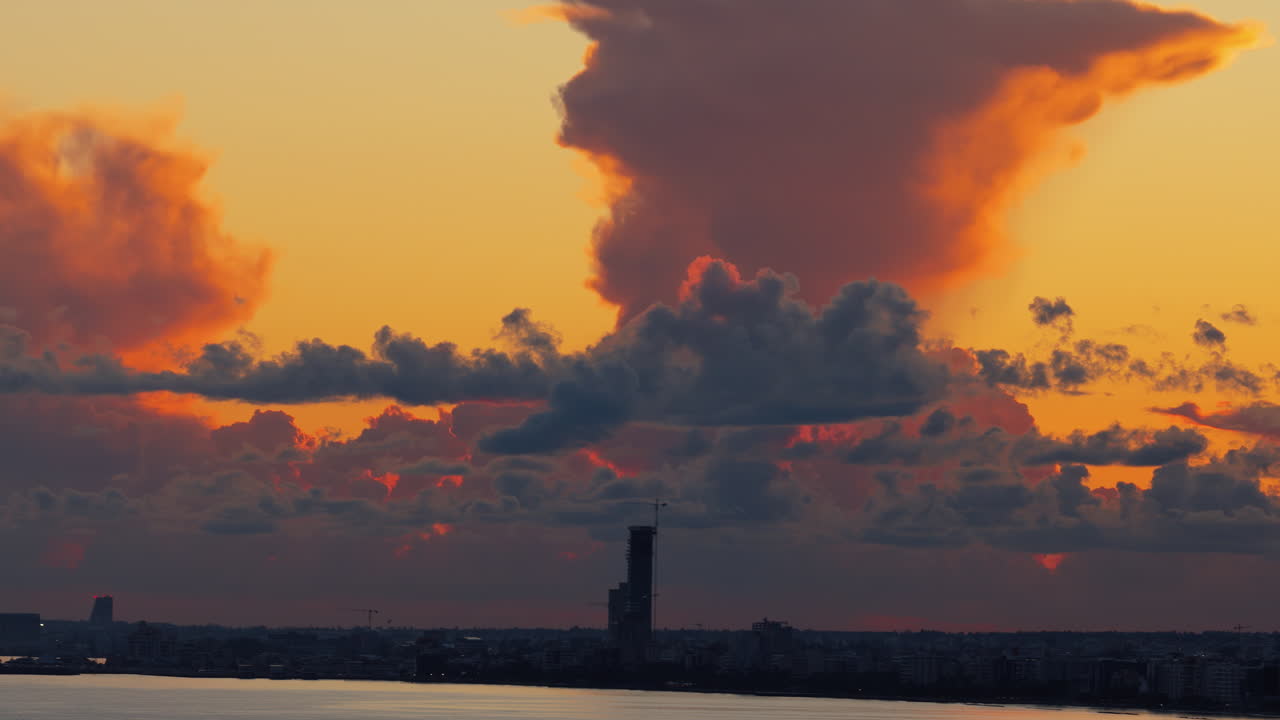 Luftaufnahme mit Drohne von modernen Hochhäusern in Limassol, beleuchtet vom warmen Sonnenlicht der goldenen Stunde bei Sonnenuntergang.