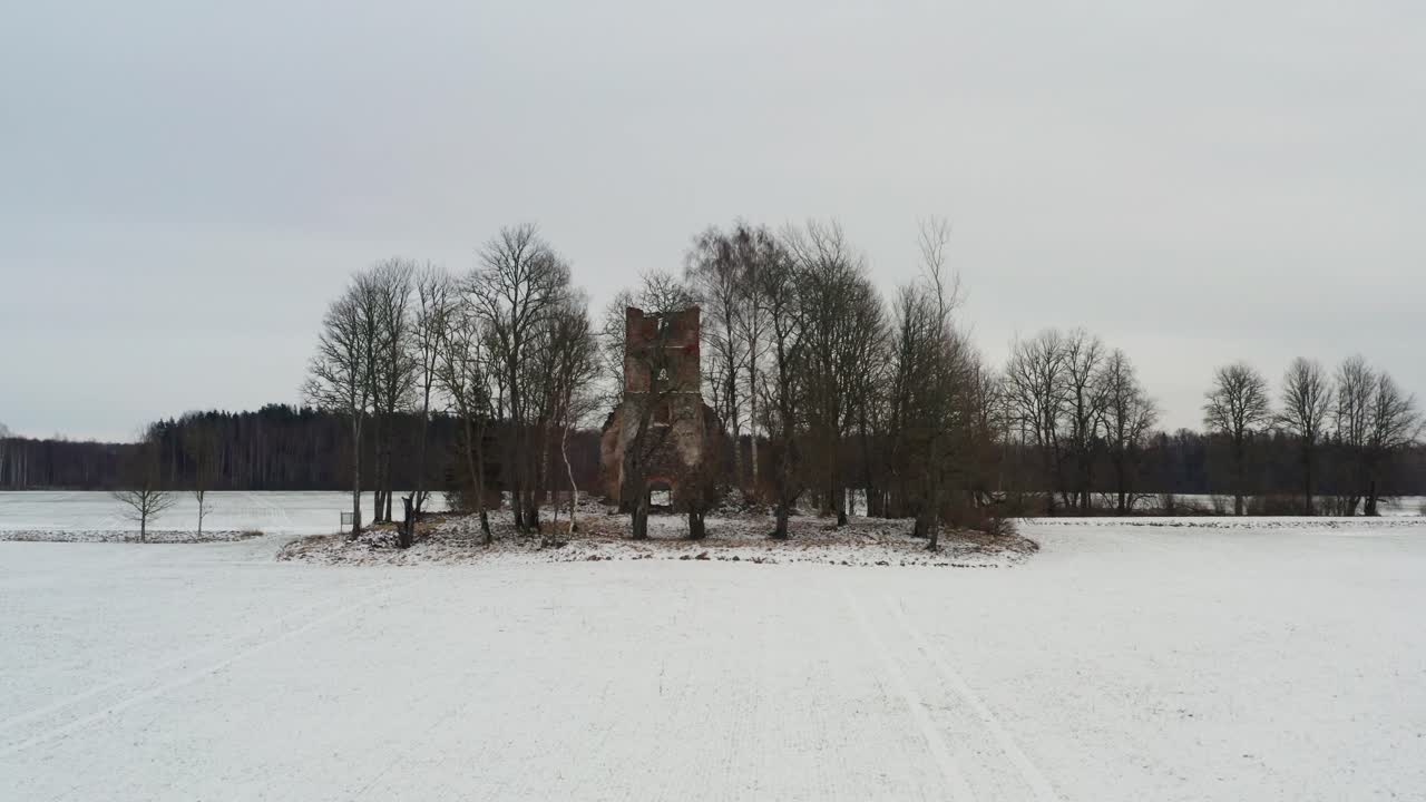 aproximación aérea baja hacia las ruinas del campanario de la iglesia abandonada, paisaje de invierno