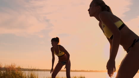 Gruppe-Junger-Mädchen,-Die-Beachvolleyball-Bei-Sonnenuntergang-Oder-Sonnenaufgang-In-Zeitlupe-Spielen.-Schöne-Mädchen-Im-Bikini-Spielen-Professionell-Volleyball-Auf-Dem-Sand