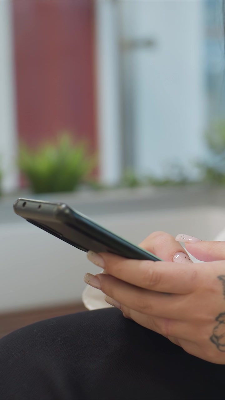 Uomo impegnato in attività digitale accanto a pelle tatuata. Smartphone posizionato vicino a un tatuaggio per una visione chiara. Scena all'aperto che enfatizza il primo piano dell'interazione con un tatuaggio sul braccio.