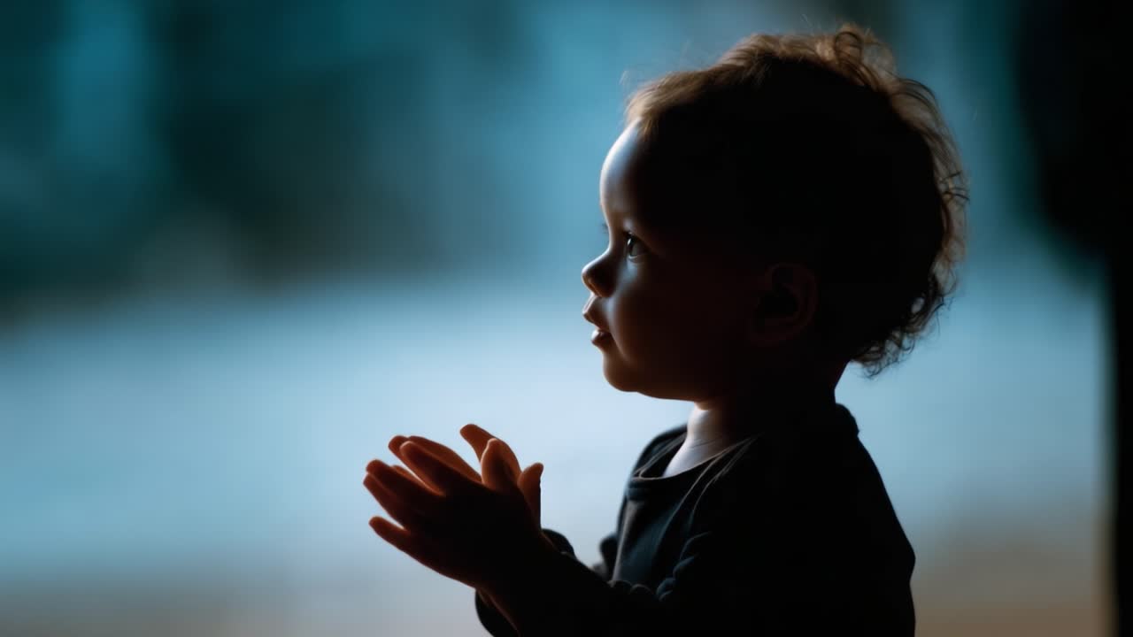 Un tenero momento contemplativo catturato nella silhouette di un bambino piccolo con capelli ricci, che irradia innocenza e meraviglia su uno sfondo delicatamente illuminato