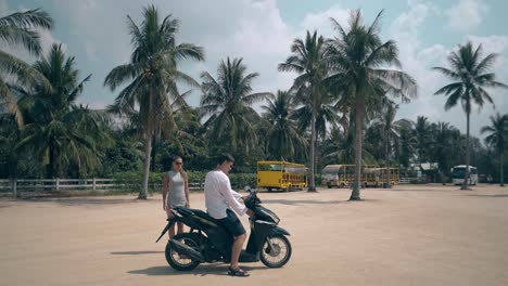 pretty woman stands near guy sitting on wonderful motorbike