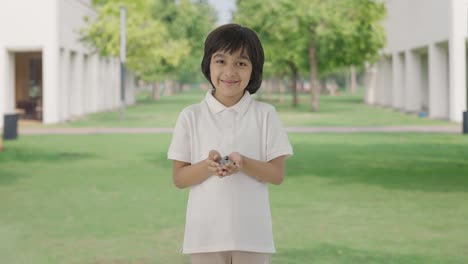 happy indian boy holding lot of coins in hand in park