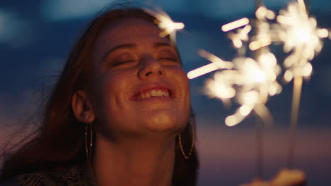 close up sparklers portrait of beautiful caucasian woman celebrating new years eve enjoying independence day celebration on beach at sunset