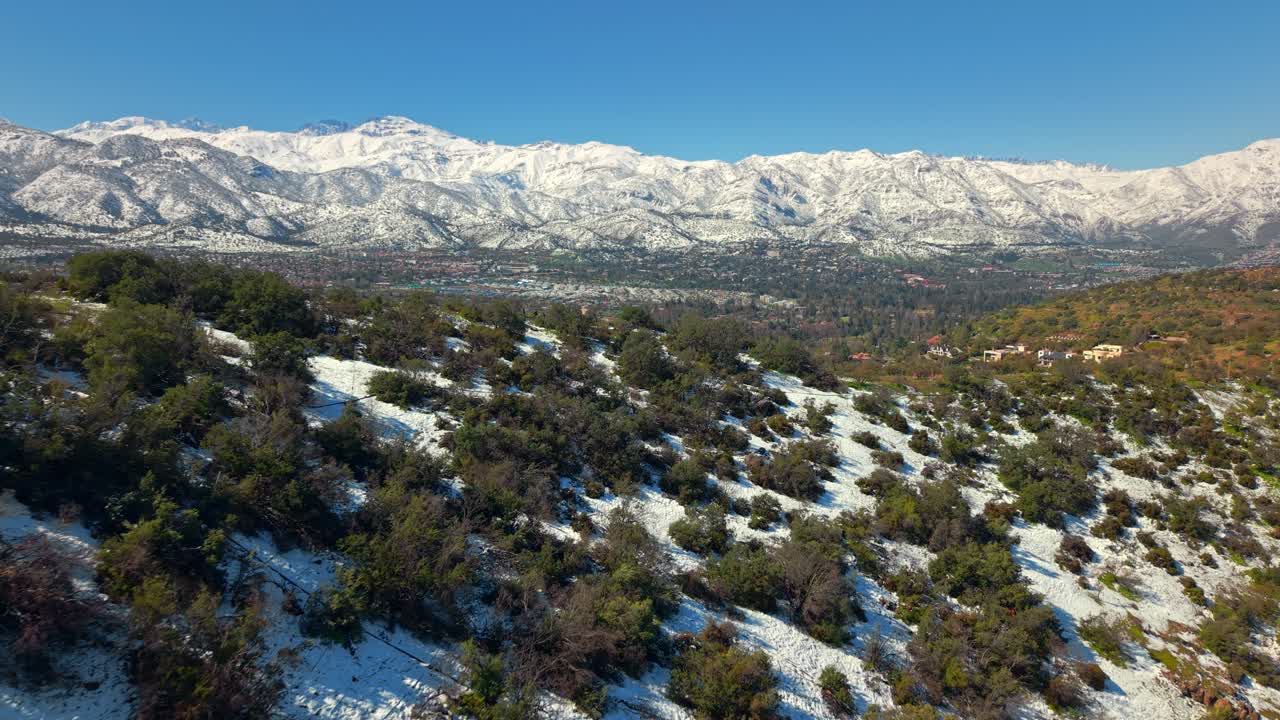 Forward dolly shot of Del Medio Hill in Lo Barnechea, framed by towering snowy Andes mountains