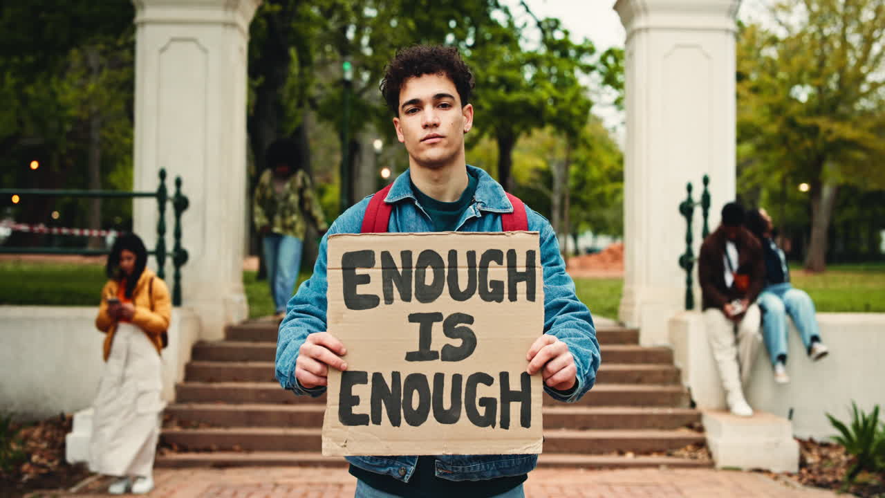 Young Man Holding 'Enough Is Enough' Protest Sign on Campus