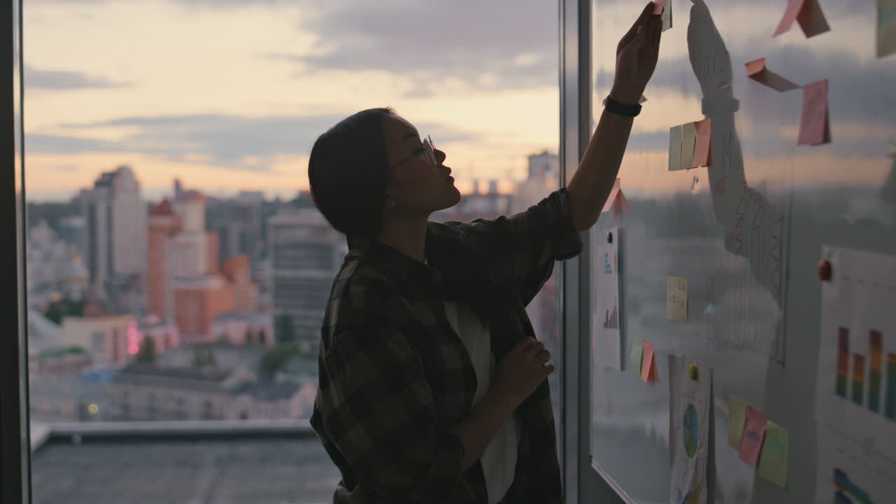 silueta de una chica examinando una pegatina al atardecer de cerca. dama haciendo una lluvia de ideas sola