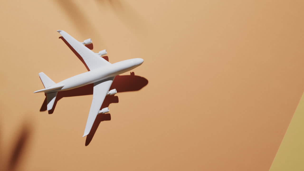 primer plano de modelo de avión blanco con sombra de hoja y espacio de copia en fondo amarillo.
