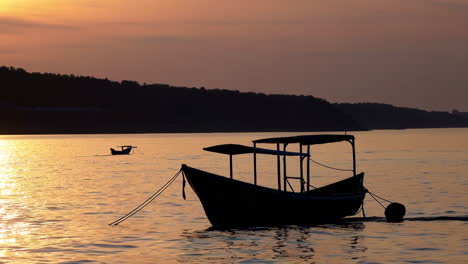 silhouette of boats at sunrise/sunset over a calm river
