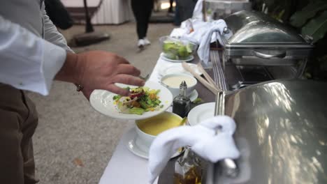 slow motion shot of a well-dressed man garnishing his plate of food at a buffet