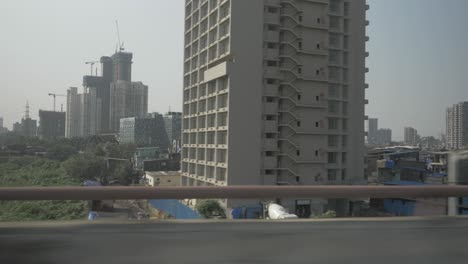 Overlooking-the-rising-sky-scrappers-of-Mumbai-against-the-foreground-of-encroaching-slums-while-travelling-on-the-eastern-express-highway