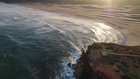 Statische-Einspielung-Der-Wellen-Des-Atlantischen-Ozeans,-Die-Bei-Sonnenaufgang-Ohne-Menschen-Gegen-Die-Klippen-Und-Den-Sand-Des-Strandes-Von-Bordeira-In-Portugal-Prallen