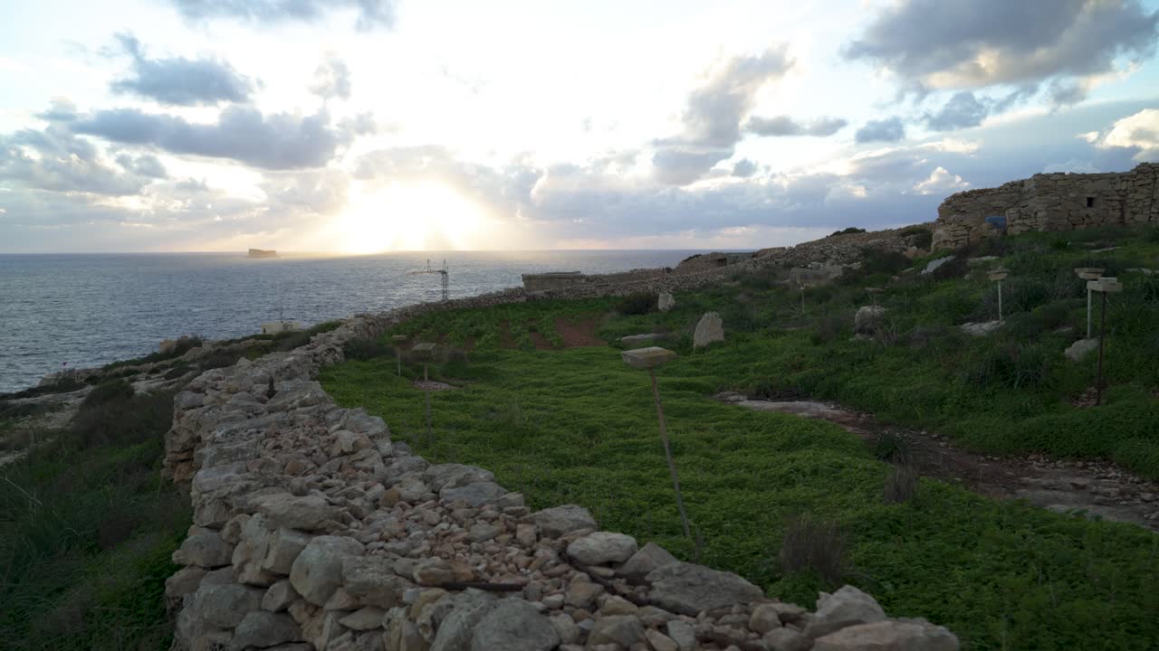 tierras de agricultores protegidas por una valla de piedra con una hermosa puesta de sol sobre el horizonte del mar mediterráneo