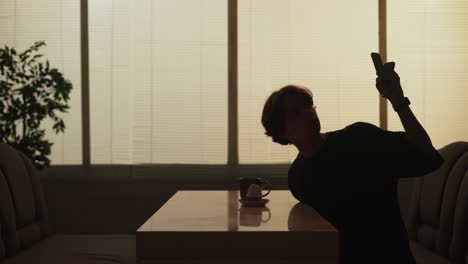 woman sitting at a table with coffee and cake, using a smartphone