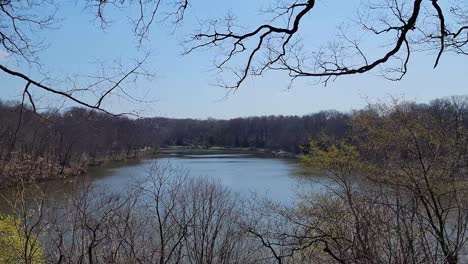 Gran-Lago-A-Principios-De-La-Primavera-Con-La-Mayoría-De-Los-árboles-Desnudos-Pero-Algunos-Comenzando-A-Brotar-Con-Cielos-Azules-Y-Barridos-De-Izquierda-A-Derecha