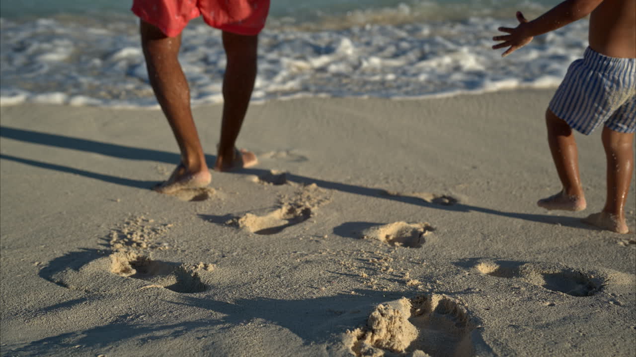 Slow motion of a mexican latin man and his son in bathing suits walking away from the camera to the sea at a beach in Cancun