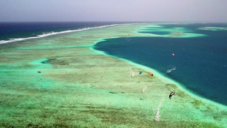 Vibrantes-Kitesurfistas-En-La-Barrera-De-Coral-De-Los-Roques-Con-Aguas-Turquesas,-Vista-Aérea