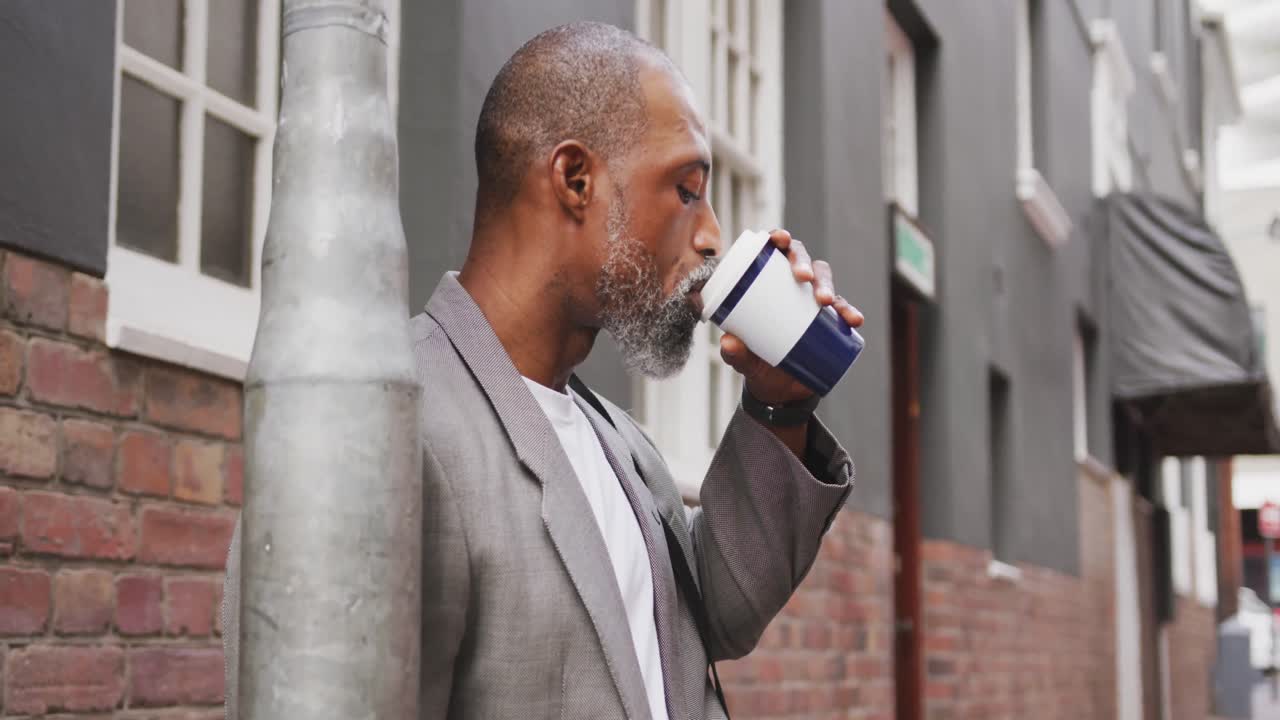 hombre afroamericano bebiendo un café y usando su teléfono