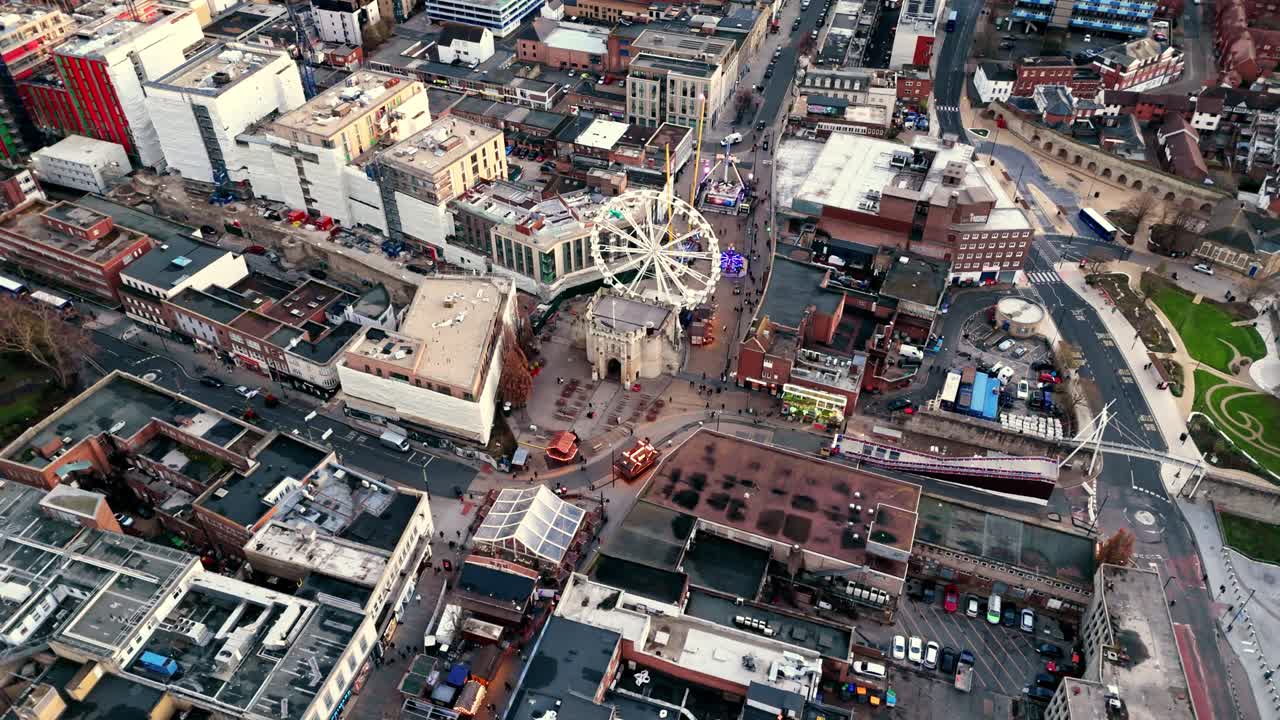 Aerial landscape drone shot panning over Southampton’s Christmas Market, showcasing glowing festive stalls, a brightly lit ferris wheel, and crowds moving through the lively winter scene