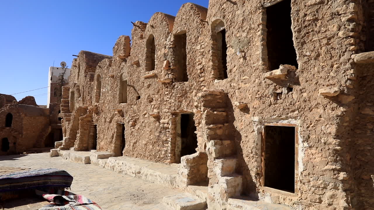 antigua carretera de ksar con edificios de piedra y ventanas arqueadas en un pueblo fortificado soleado en tunisia