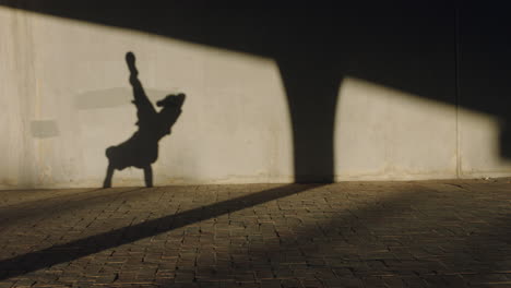 Tanzender-Mann,-Schatten-Eines-Jungen-Breakdancers,-Der-Freestyle-Tanzbewegungen-Im-Handstand-Ausführt,-Geeigneter,-Gemischtrassiger-Mann,-Der-Bei-Sonnenuntergang-In-Der-Stadt-übt