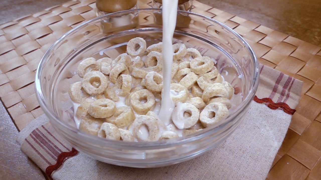 Fiocchi d'avena croccanti in una ciotola per una deliziosa colazione mattutina con latte. Slow motion con ripresa rotatoria.