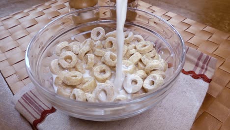 copos de avena crujientes en un tazón para un delicioso desayuno matutino con leche. cámara lenta con toma de seguimiento de rotación.