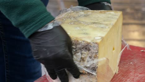 preparing aged cheese at a market