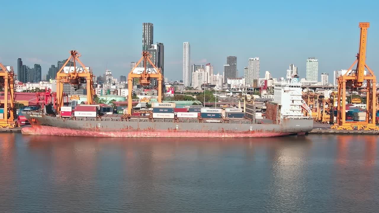 View of cargo ship in Bangkok harbor with city skyline in background