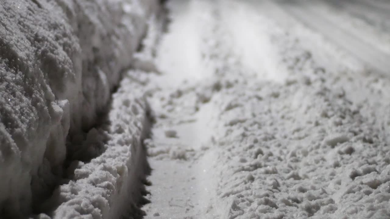 todavía una foto de una carretera cubierta de nieve, con huellas de neumáticos pasando por