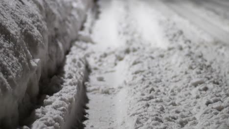 still shot of a snow covered road, with tire tracks going through