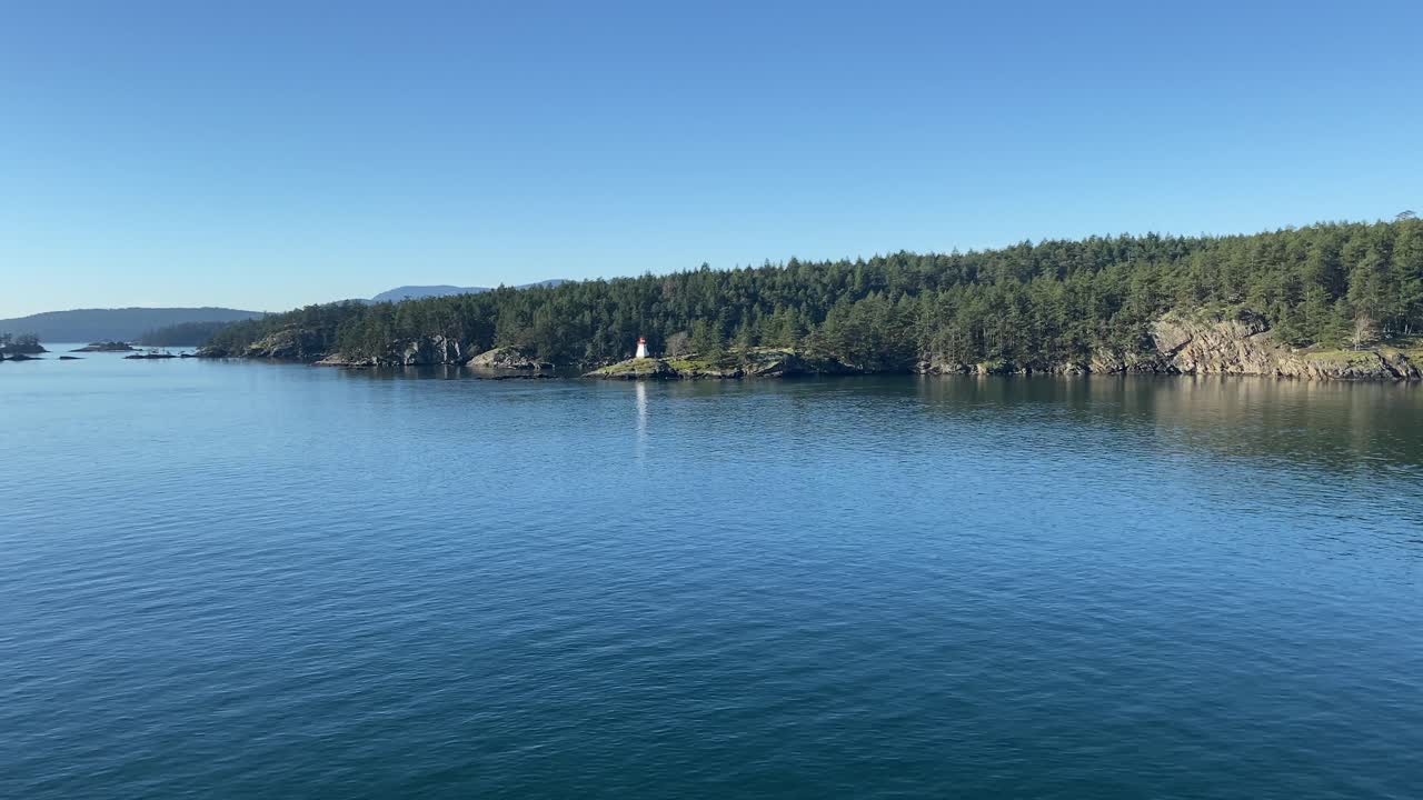 vista del paisaje costero de un faro blanco rodeado de pinos y aguas tranquilas del océano