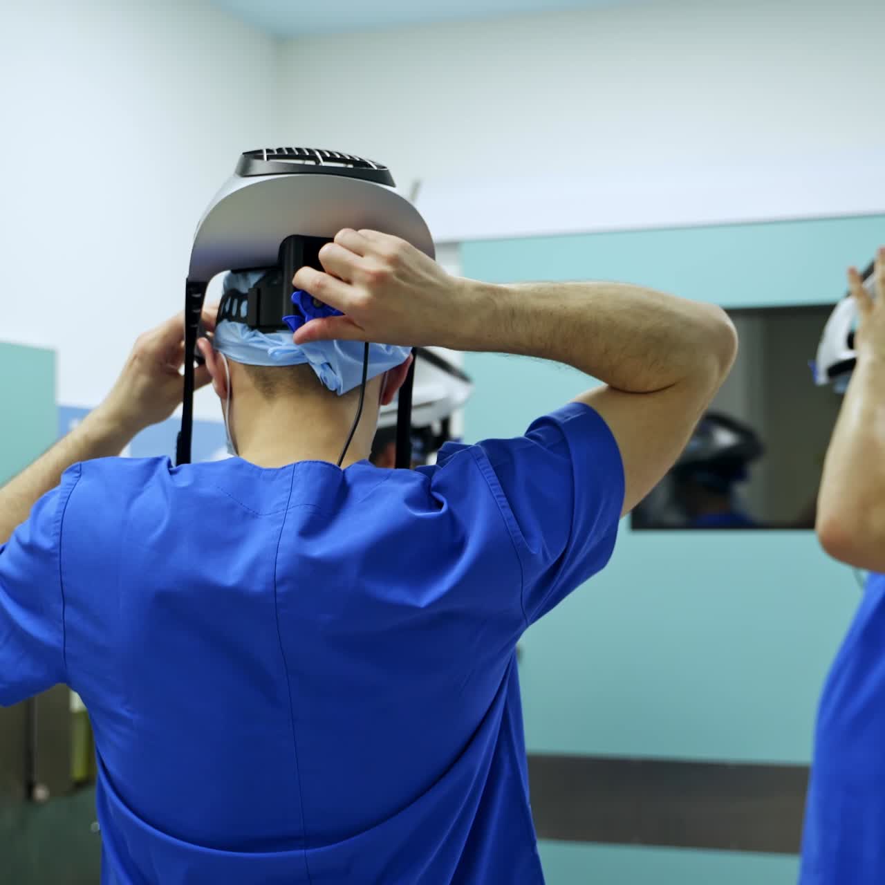 Three surgeons put on special helmets to wear under the protective suits. Doctors prepare for procedure in the pre-operational room