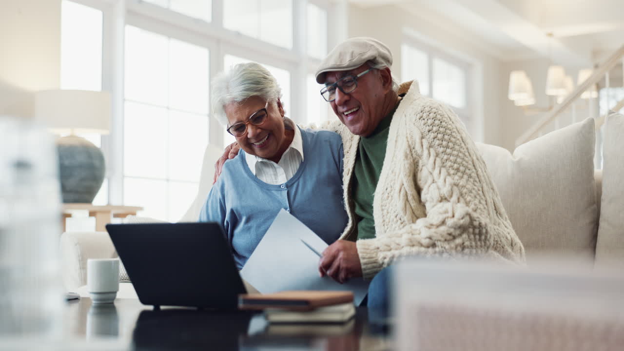 Happy senior couple laughing while looking at a laptop.