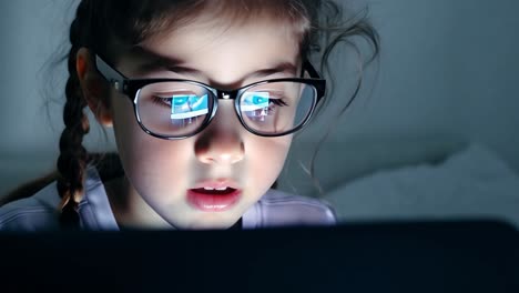 una joven con gafas mirando una pantalla de computadora