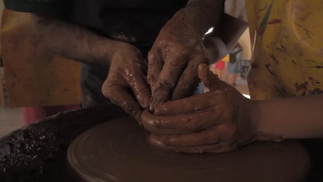 Taller-De-Alfarería,-Cerca-De-Las-Manos-Tirando-Arcilla-En-La-Rueda-De-Alfarería,-Profesor-Con-Niño