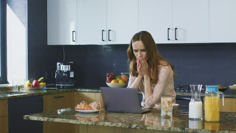 mujer asustada viendo un video en la computadora. mujer de negocios preguntándose en la nueva cocina