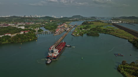 panama city aerial v31 pull out shot of cargo tanker ship transiting at canal locks towards pacific ocean from miraflores lake with cityscape in the skyline - shot with mavic 3 cine - march 2022