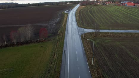 Hombre-Esquiando-Por-Una-Larga-Y-Aislada-Carretera-Rural-Húmeda-Cerca-De-Ostersund,-Suecia