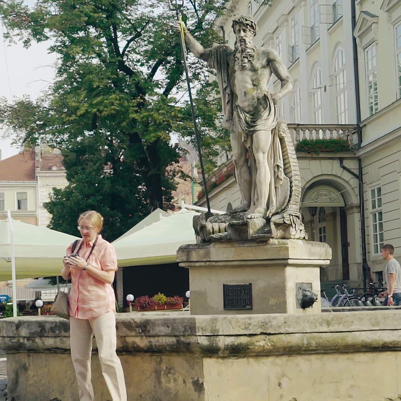 Monumento architettonico nel centro città e turisti che passeggiano e scattano foto. Antico memoriale nella via centrale di una città.
